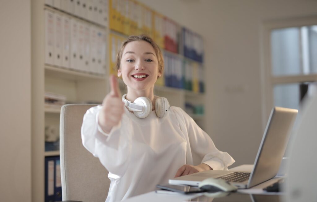 woman wearing white top while doing thumbs up